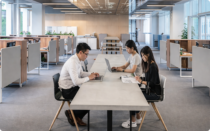 Office employees working with laptops and documents in a modern open-plan workspace